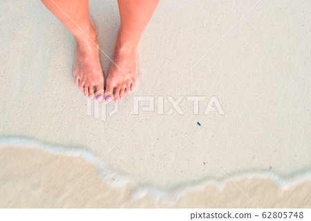 Woman's feet on the white sand beach in shallow water Woman's feet on the white sand beach in shallow water 62805748