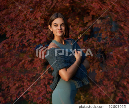 Beautiful girl in the park in front of red leaf wall Beautiful girl in the park in front of red leaf wall 62805935