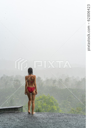 Barefoot girl standing on the edge on an infinity pool 62806423