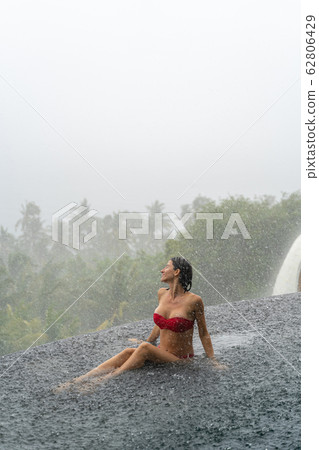 Woman turning her face up to the rain 62806429