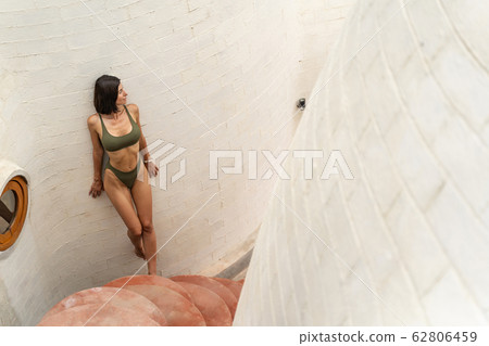 Dark-haired girl with bracelets standing at a wall 62806459