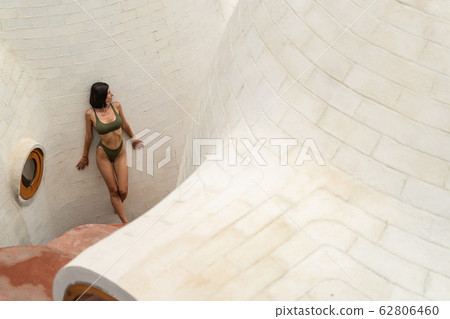 Barefoot female vacationist standing near a limestone building 62806460
