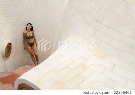 Calm young woman standing near a limestone wall 62806461