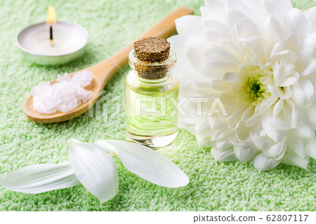 Close-up of chrysanthemum essential oil, white chrysanthemum, sea salt and burning aromatic candle 62807117