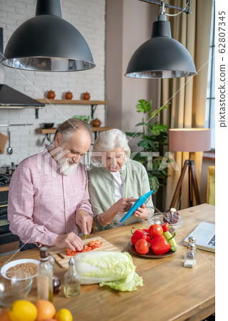 Elderly couple using recipes from the internet while cooking 62807345