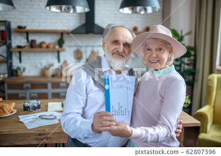 Smiling elderly couple preparing tickets for their flight Smiling elderly couple preparing tickets for their flight 62807396
