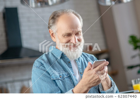 Smiling elderly man using his new smartphone Smiling elderly man using his new smartphone 62807440