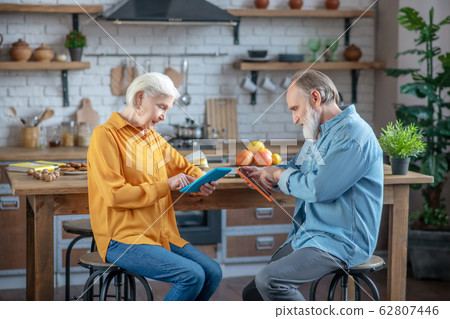 Elderly man and woman using tablets for surfing internet Elderly man and woman using tablets for surfing internet 62807446