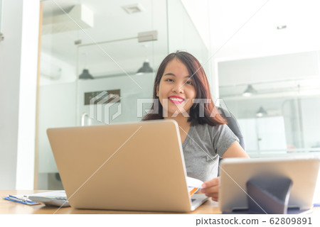 Smiling businesswoman sitting in business office 62809891