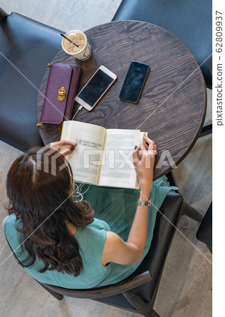 Asian lady using smartphone and reading book while having coffee 62809937