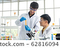 Science, Chemistry, Technology, Biology and Laboratory concept - Asian junior scientist is showing experimental results in test tube to Asian Senior scientist. 62816094