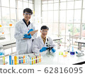 Science, Chemistry, Technology, Biology and Laboratory concept - Portrait of Asian junior scientist is taking notes and Asian Senior scientist works with his microscope. 62816095