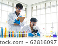 Science, Chemistry, Technology, Biology and Laboratory concept - Asian junior scientist taking notes while Asian Senior scientist looks into something on a petri dish. 62816097