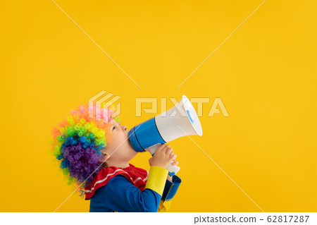 Funny kid clown playing against yellow background 62817287