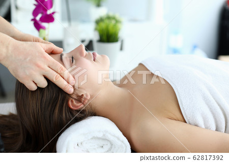 Hands massage whiskey to girl who lying on towel Hands massage whiskey to girl who lying on towel 62817392