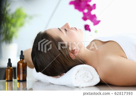 Girl lies in massage parlor, near aromatic oils Girl lies in massage parlor, near aromatic oils 62817393