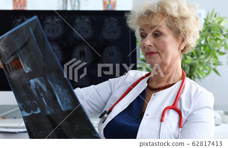 Experienced doctor woman looking at MRI picture Experienced doctor woman looking at MRI picture 62817413