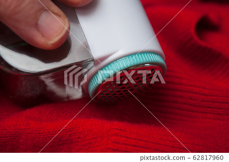 Closeup of balls shaving on red woolen pullover Closeup of balls shaving on red woolen pullover 62817960
