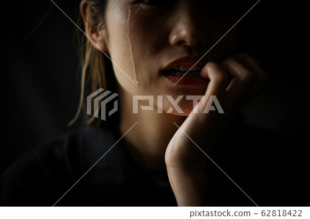 Woman biting nails while shedding tears 62818422