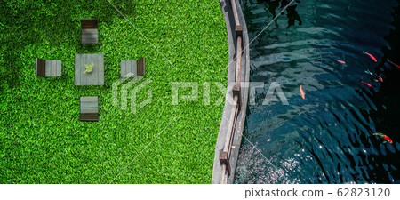Top view of fresh water in pond with green grass meadow field and wooden chair in outdoor garden. Top view of fresh water in pond with green grass meadow field and wooden chair in outdoor garden. 62823120