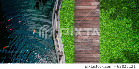 Top view of fresh water in pond with green grass meadow field with wooden walkway in outdoor garden. Top view of fresh water in pond with green grass meadow field with wooden walkway in outdoor garden. 62823121