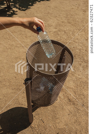 Hand of woman throwing a plastic bottle in a trash can at Merida Hand of woman throwing a plastic bottle in a trash can at Merida 62827471