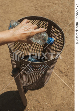 Hand of woman throwing a plastic bottle in a trash can at Merida Hand of woman throwing a plastic bottle in a trash can at Merida 62827473