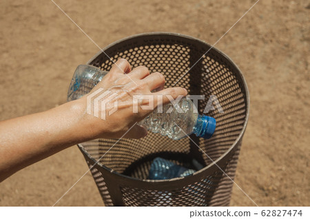 Hand of woman throwing a plastic bottle in a trash can at Merida Hand of woman throwing a plastic bottle in a trash can at Merida 62827474