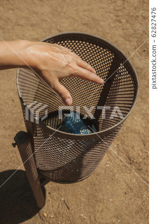 Hand of woman throwing a plastic bottle in a trash can at Merida Hand of woman throwing a plastic bottle in a trash can at Merida 62827476