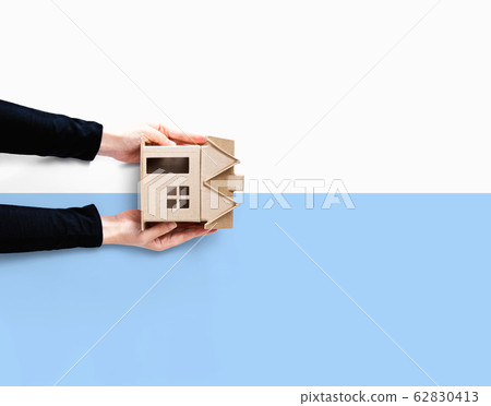 Woman holding a cardboard house 62830413