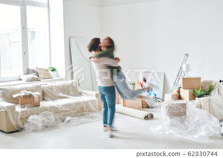 Blurry outline of young man whirling his happy wife in the center of living-room Blurry outline of young man whirling his happy wife in the center of living-room 62830744