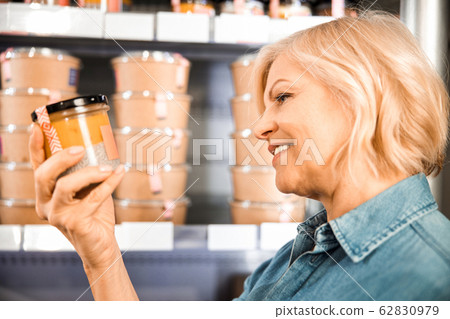 Happy attractive lady reading information on products in store Happy attractive lady reading information on products in store 62830979