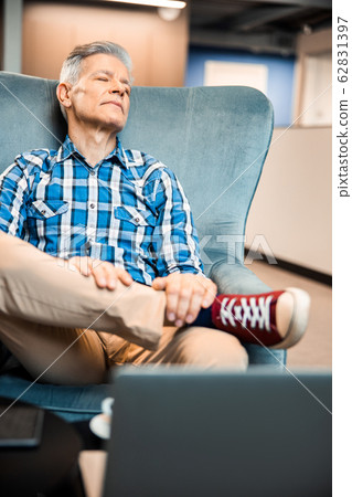 Stylish adult man sitting in armchair and relaxing 62831397