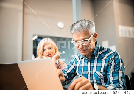 Smiling adult man looking at laptop screen 62831442