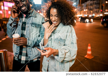 Happy Afro American lady looking on smartphone screen outdoors 62832077