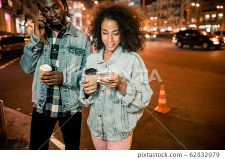 Pretty smiling woman reading messages on the phone in the city 62832079
