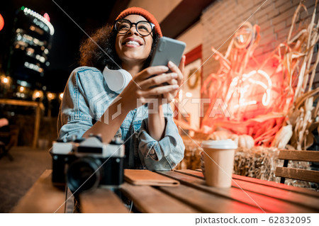 Pretty smiling lady holding phone and looking away outdoors Pretty smiling lady holding phone and looking away outdoors 62832095