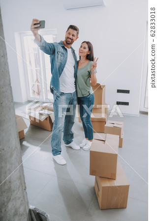 Happy couple is using mobile phone in new flat Happy couple is using mobile phone in new flat 62833018