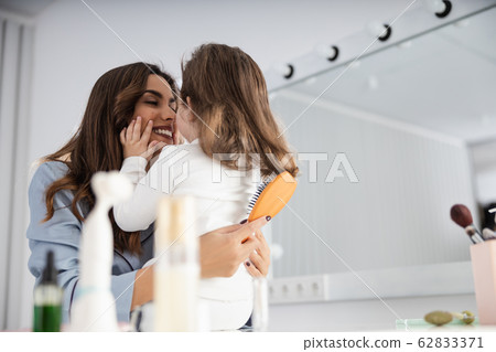 Happy pretty mom helping her daughter with hair Happy pretty mom helping her daughter with hair 62833371