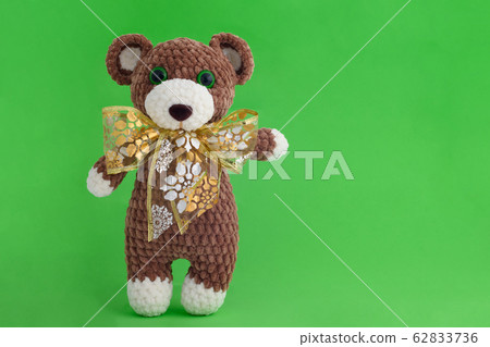 Children's knitted toy bear with bow on a green Children's knitted toy bear with bow on a green 62833736