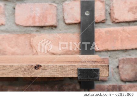Shelf in wood and metal hanging on a brick wall in Shelf in wood and metal hanging on a brick wall in 62833806