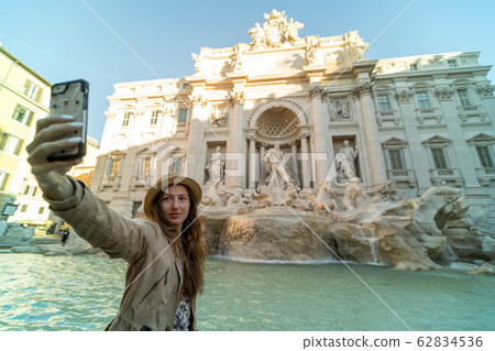 Selfie of young woman on the background of Trevi Fountain, Rome, Italy. Fontana di Trevi is one of the main tourist attractions of Rome. People visit the Rome landmark. Traveling and vacation in Rome. Selfie of young woman on the background of Trevi Fountain, Rome, Italy. Fontana di Trevi is one of the main tourist attractions of Rome. People visit the Rome landmark. Traveling and vacation in Rome. 62834536