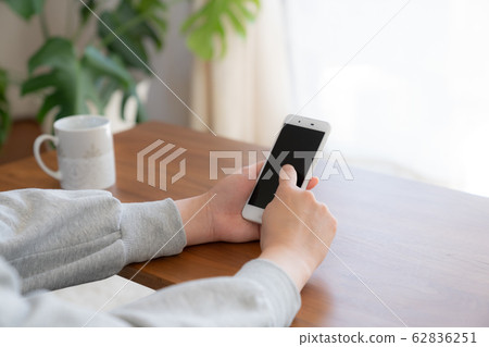 一名操作智能手機/在家的女人 一名操作智能手機/在家的女人 62836251