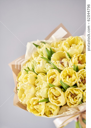 Yellow pastel color tulips in woman hand. Young beautiful woman holding a spring bouquet. Bunch of fresh cut spring flowers in female hands 62844796