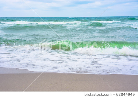 waves crash on sandy beach 62844949