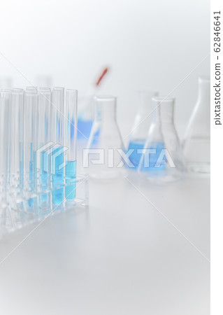 Laboratory glassware with blue liquid into test tube and flask with copyspace 62846641