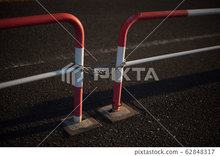 Chain and padlock on fence beside road 62848317