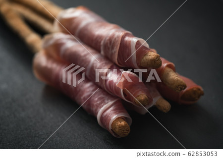 grissini breadsticks with prosciutto on slate background 62853053