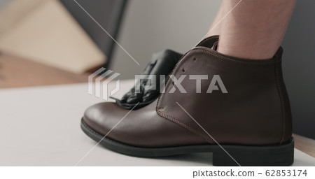man hands in black gloves applying protective cream to brown leather chukka boots 62853174