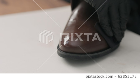 man hands in black gloves applying protective cream to brown leather chukka boots 62853175